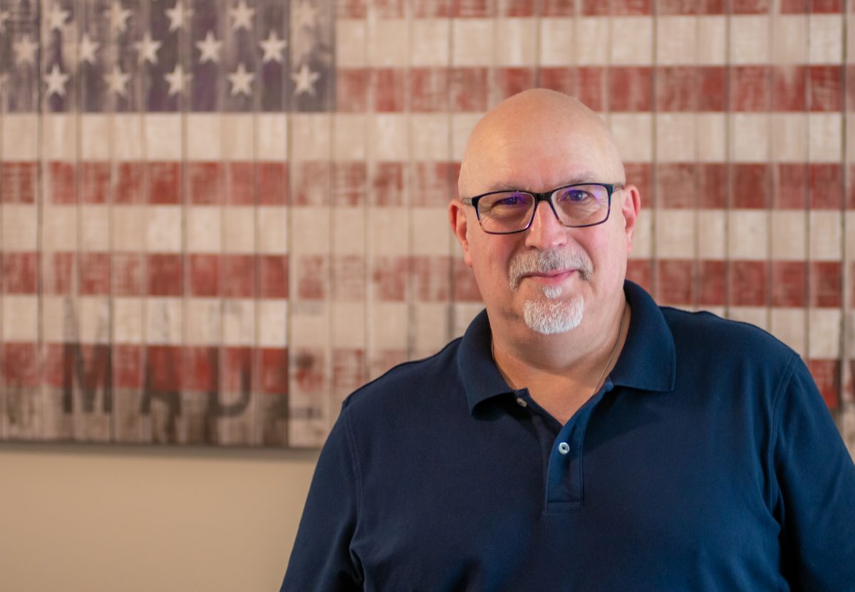Portrait of Andrew, Sales Performance Coach at Pepperl+Fuchs. Behind him you can see the American flag.