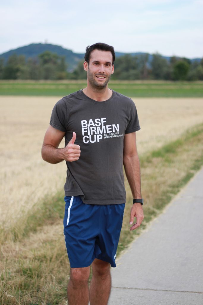 André, Product Compliance Engineer at Pepperl+Fuchs, stands on a path in the middle of fields and is ready to start jogging.