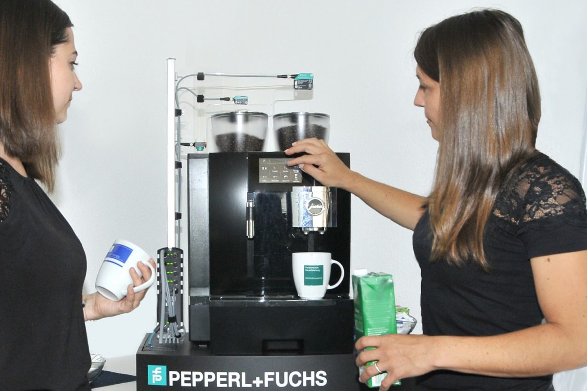 The smart coffee machine equipped with sensors and a cloud connection makes it possible for people to experience and understand the possibilities of the Internet of Things. You can see two girls next to the coffee machine.