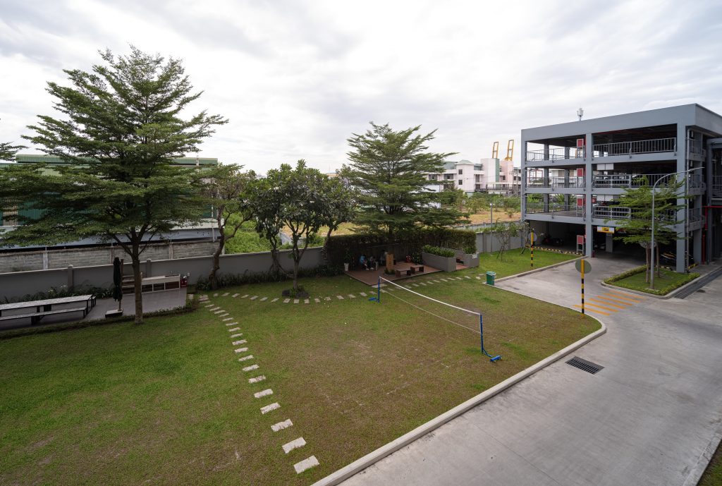 View from above of a badminton court. To the left is the terrace with seating and outdoor kitchen, to the right is the parking garage.