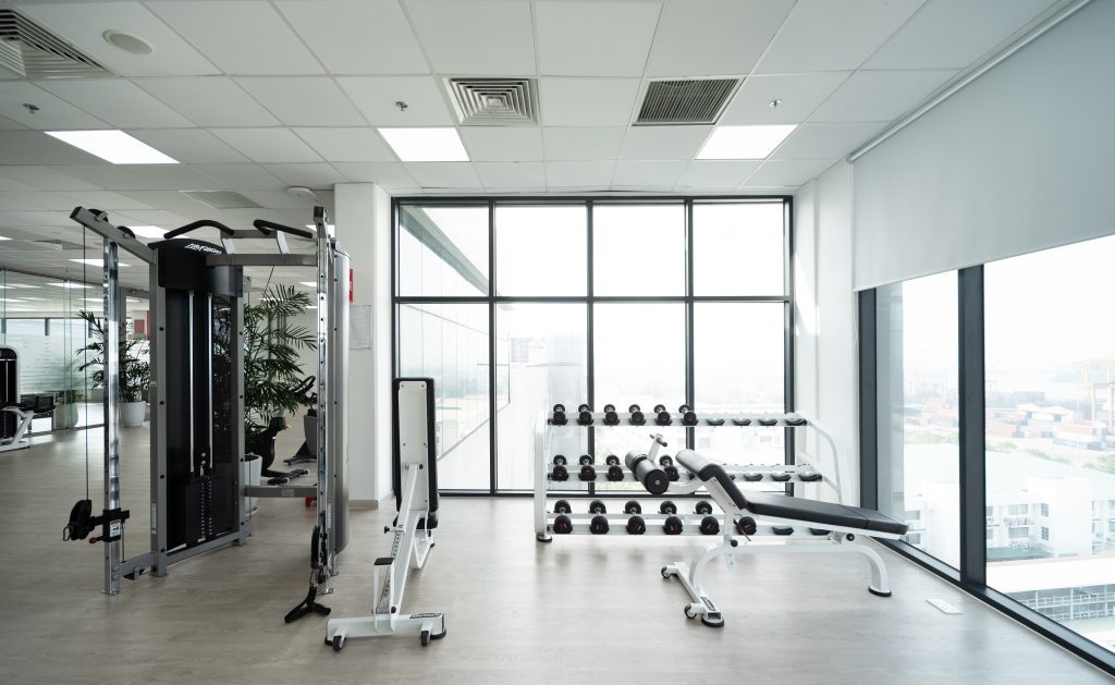 View of a weight bench in the gym. In the background there is a shelf with different weights.