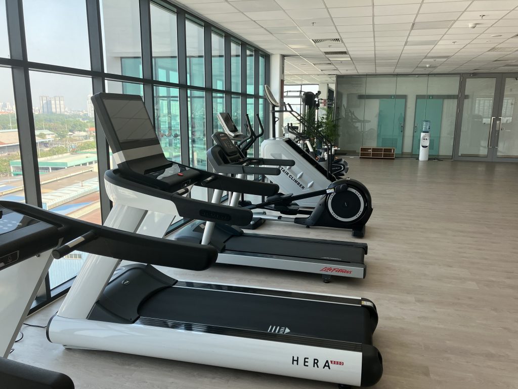 View of the fitness studio: There are various fitness machines such as treadmills and bicycles on the left side of the window.