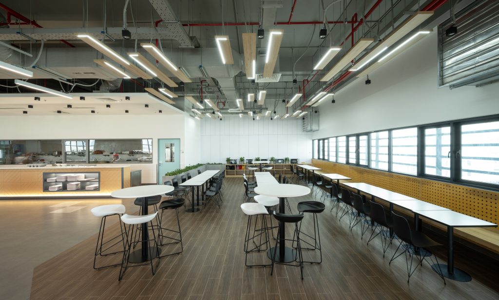 Insight into the canteen at Pepperl+Fuchs Vietnam. On the left you can see the food serving area, on the right you can see several white tables with black chairs.