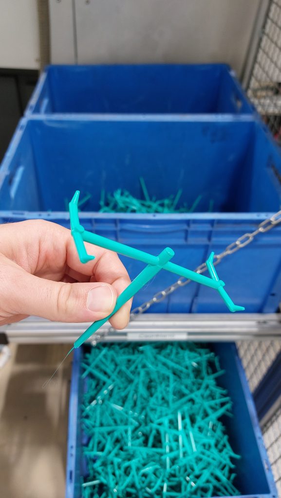 A box full of sprues sits on the floor. A hand can be seen holding one close to the camera.