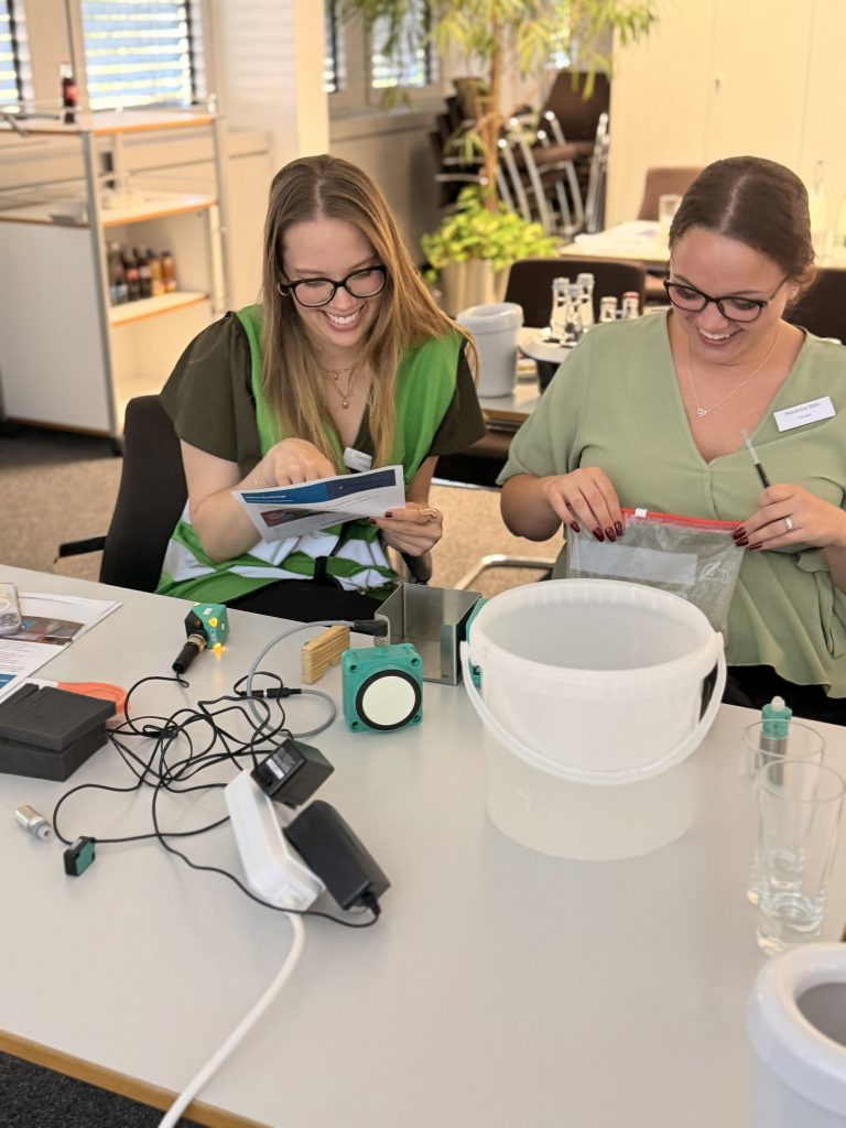 Two participants in the Sonepar Apprentice Days are seated at a table, actively working with Pepperl+Fuchs products.